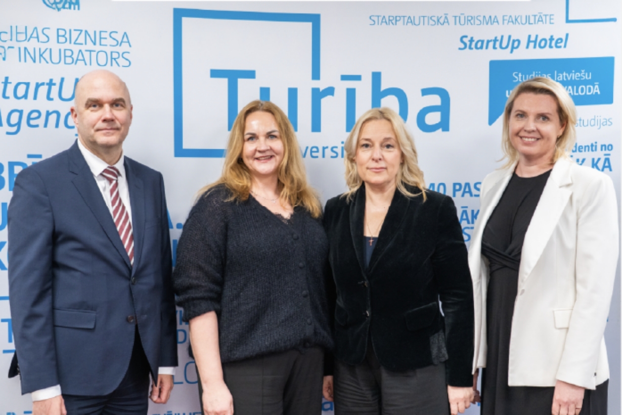 Turība universitātes baneris ar četriem cilvēkiem pie tā