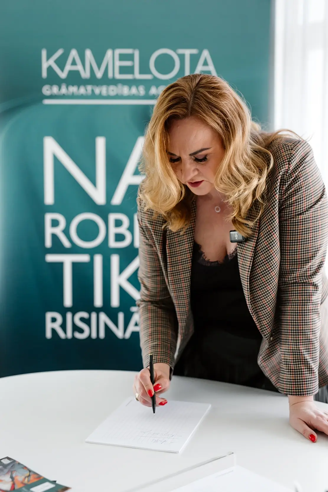 Kamelota uzņēmuma vadītāja veic pierakstus uz papīra