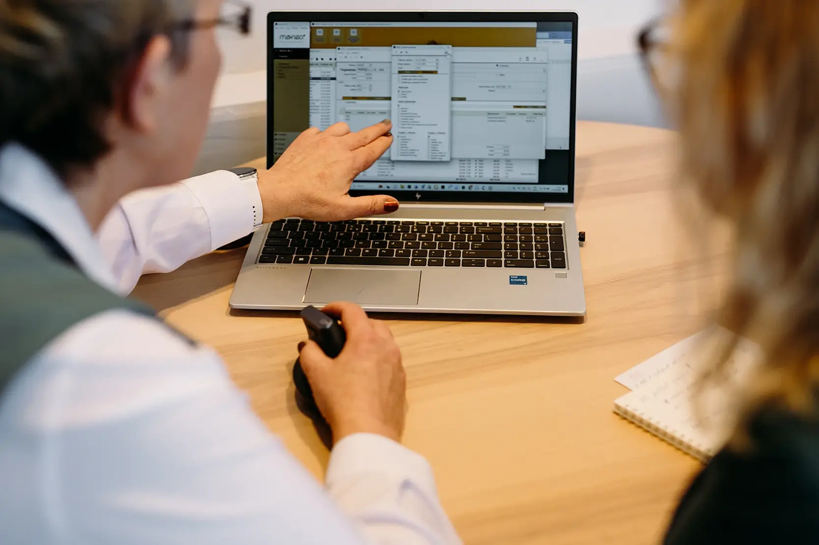 Kamelota darbiniece sniedz konsultāciju klientam un rāda rezultātus datorā